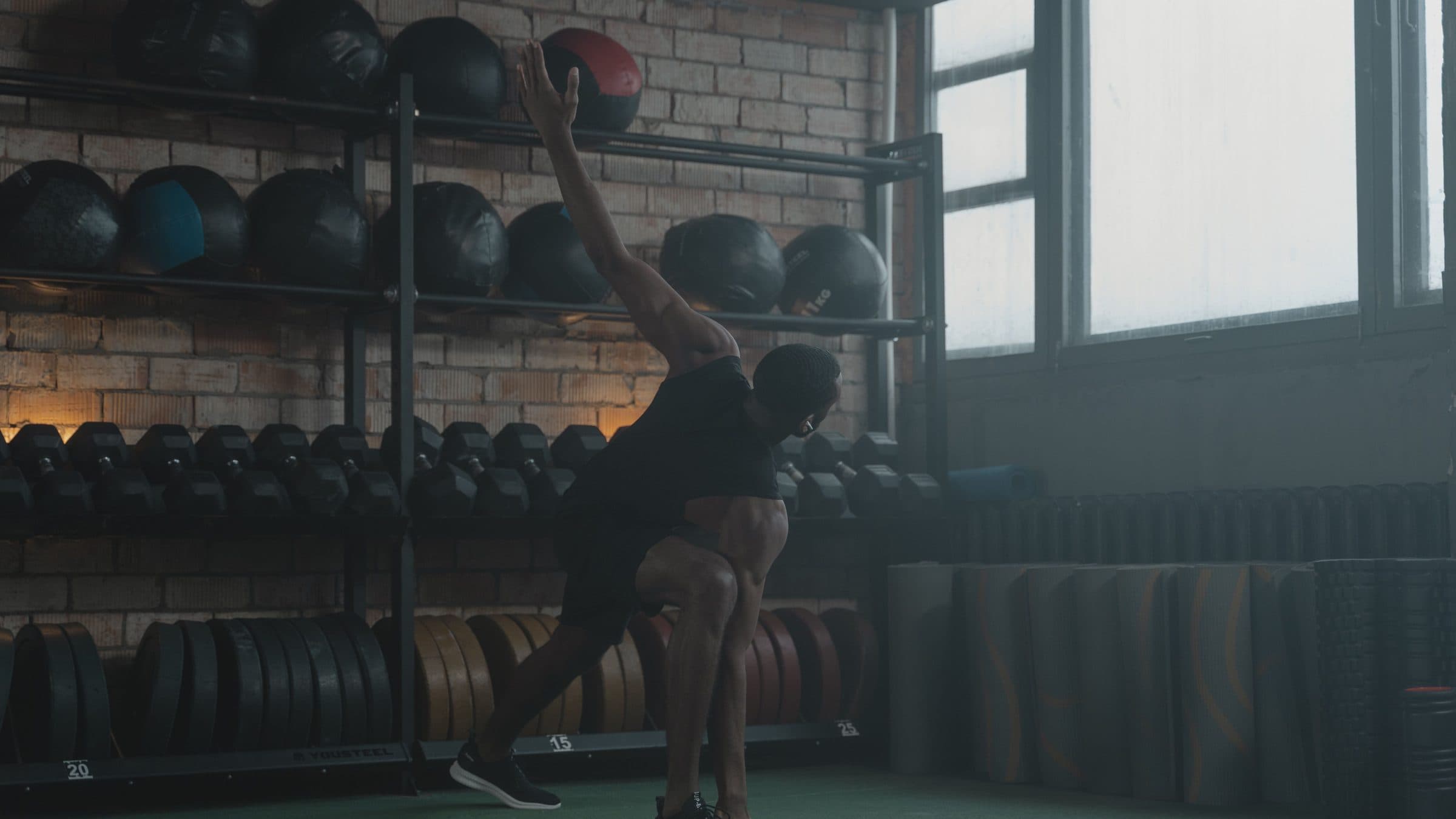 Athlete performing a kettlebell movement in a sunlit gym