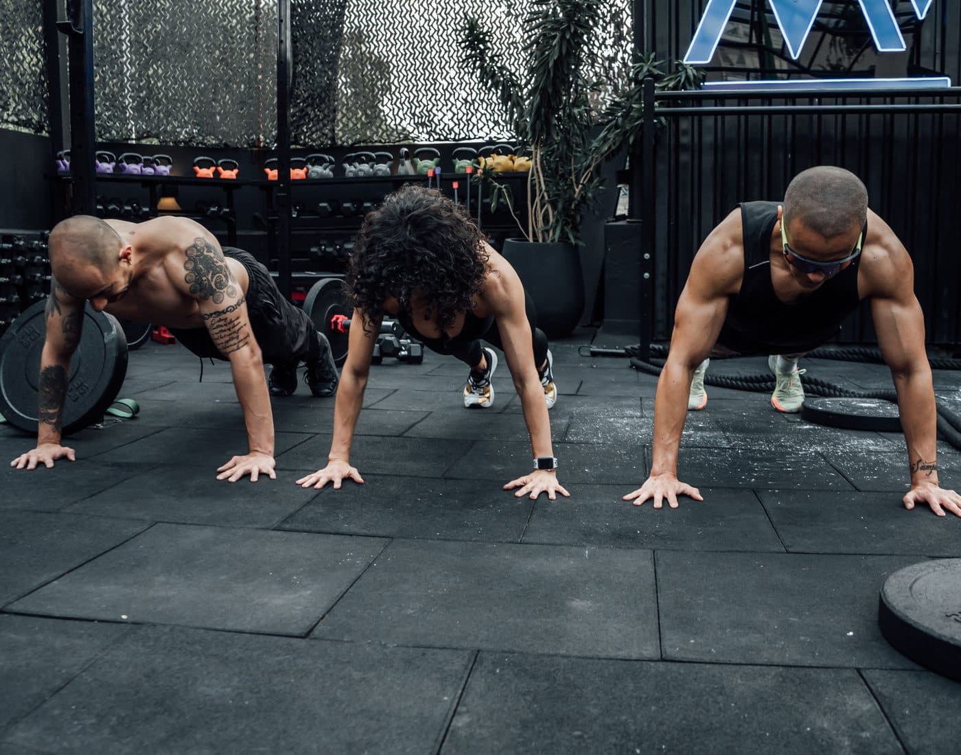 Three people training together on a gym floor